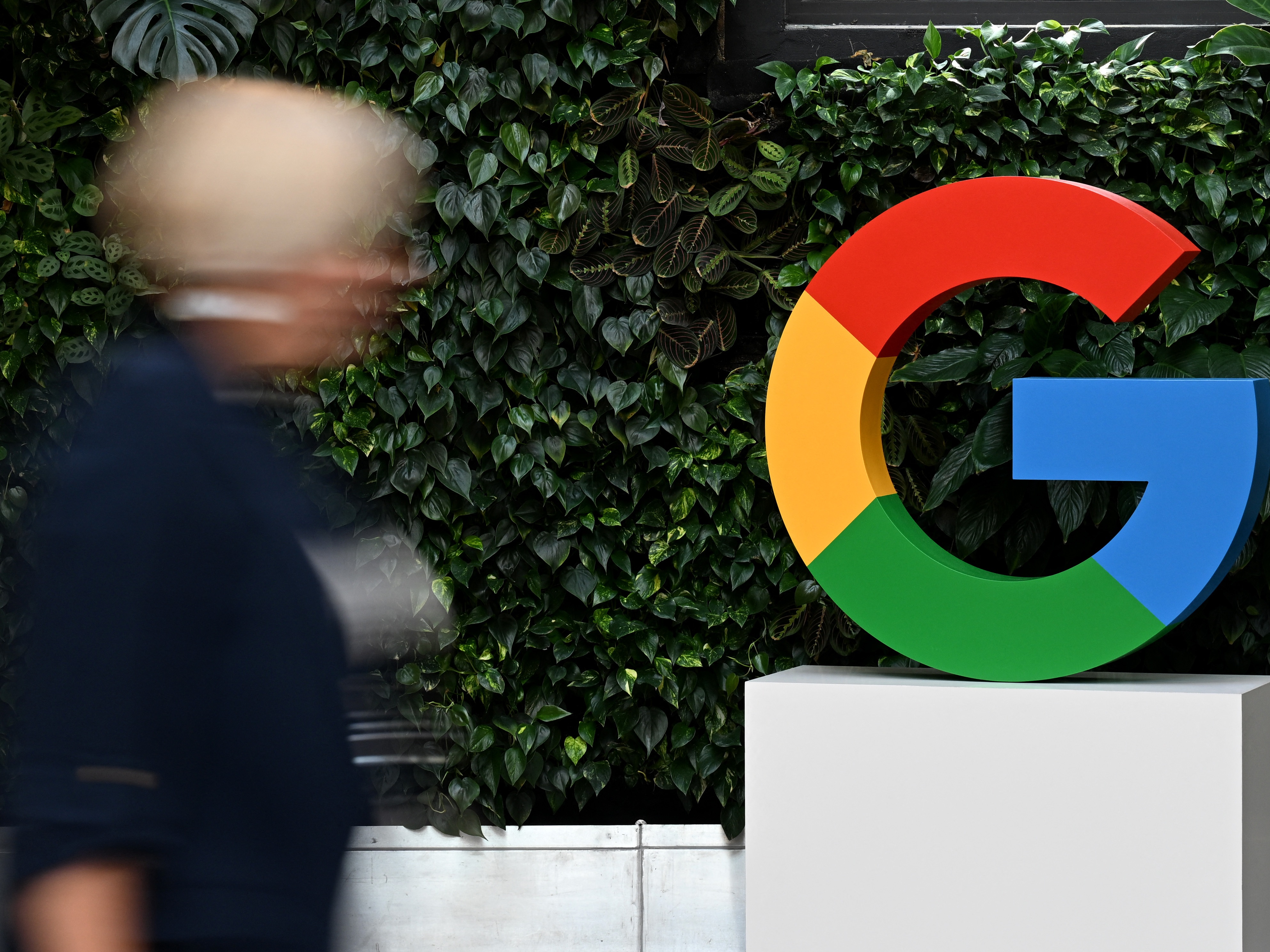 caption: A woman walks past a Google logo at the Google Campus in Warsaw on Feb.13, 2025.