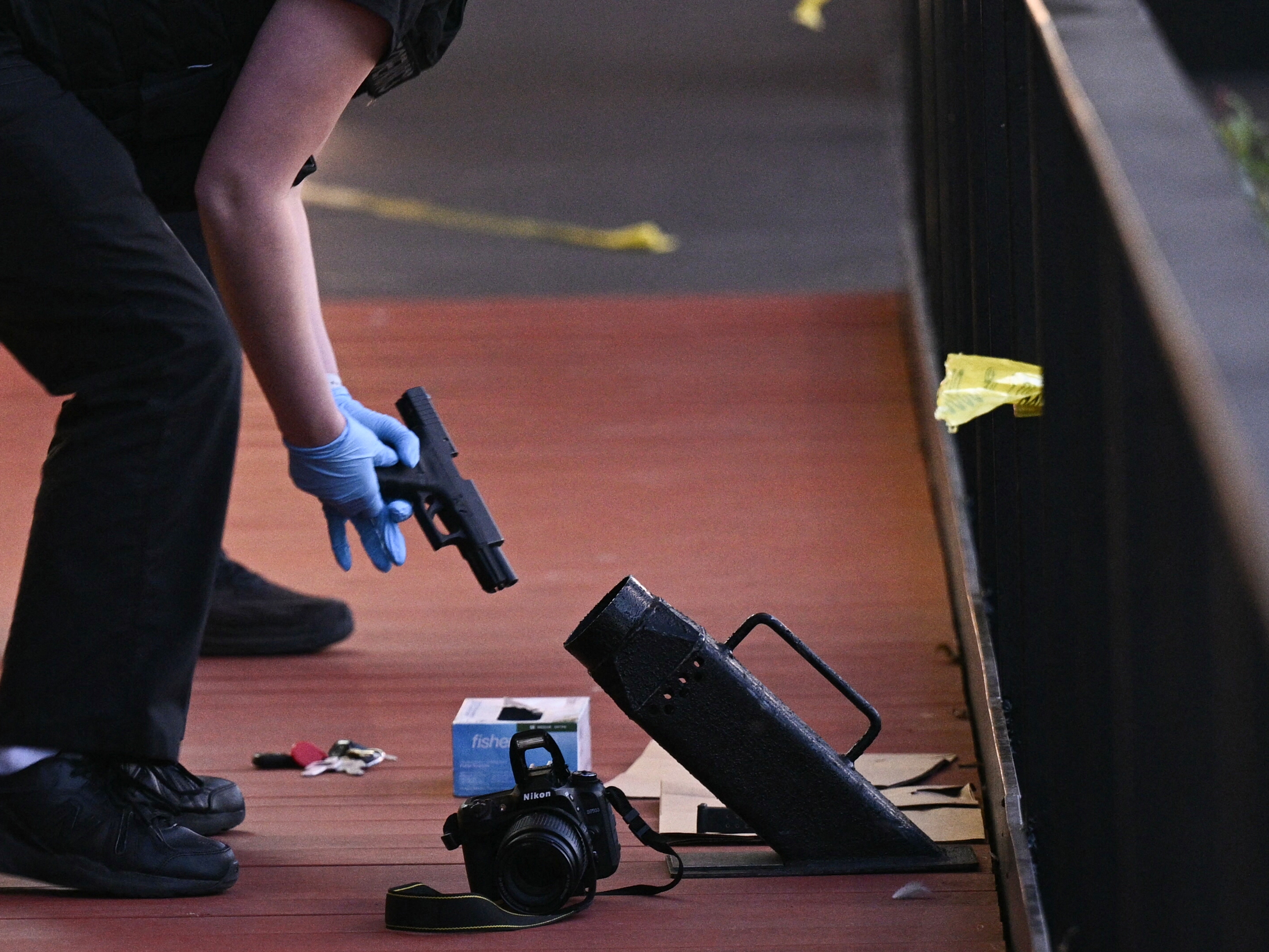 caption: A law enforcement officer inspects a handgun at the scene of a shooting in Washington, D.C., on Oct. 2.