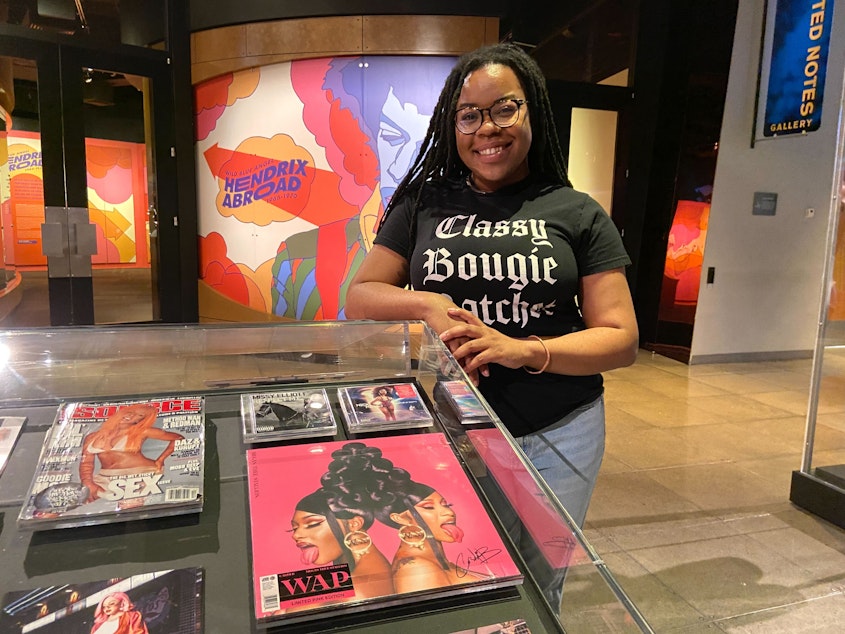 caption: MoPop guest curator and hip-hop feminist scholar Adeerya Johnson stands next to a display at "My Mic Sounds Nice: Hip-Hop Feminism in History. 