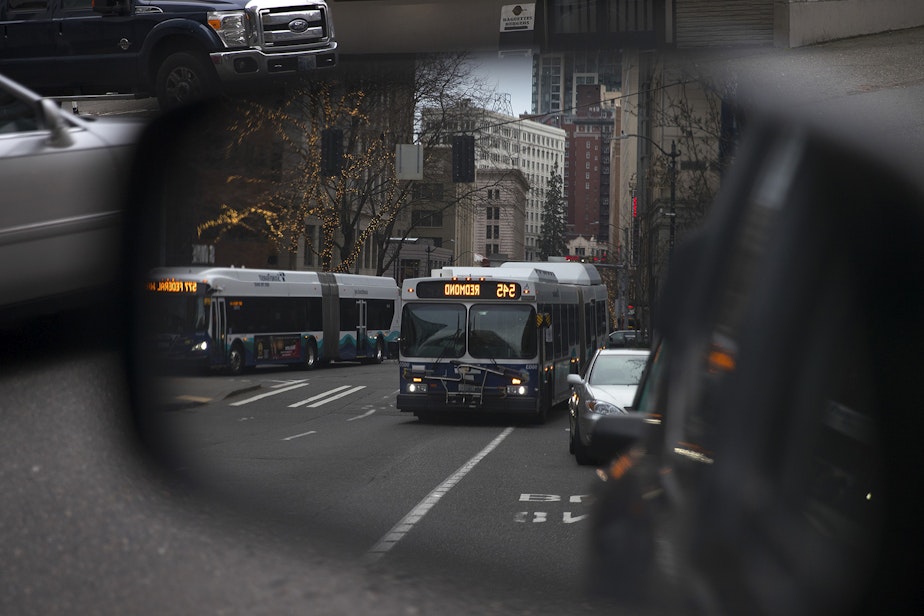 caption: A bus is shown in a rearview mirror on Olive Way near the intersection of 9th Ave., on Tuesday, January 2, 2018, in Seattle. 