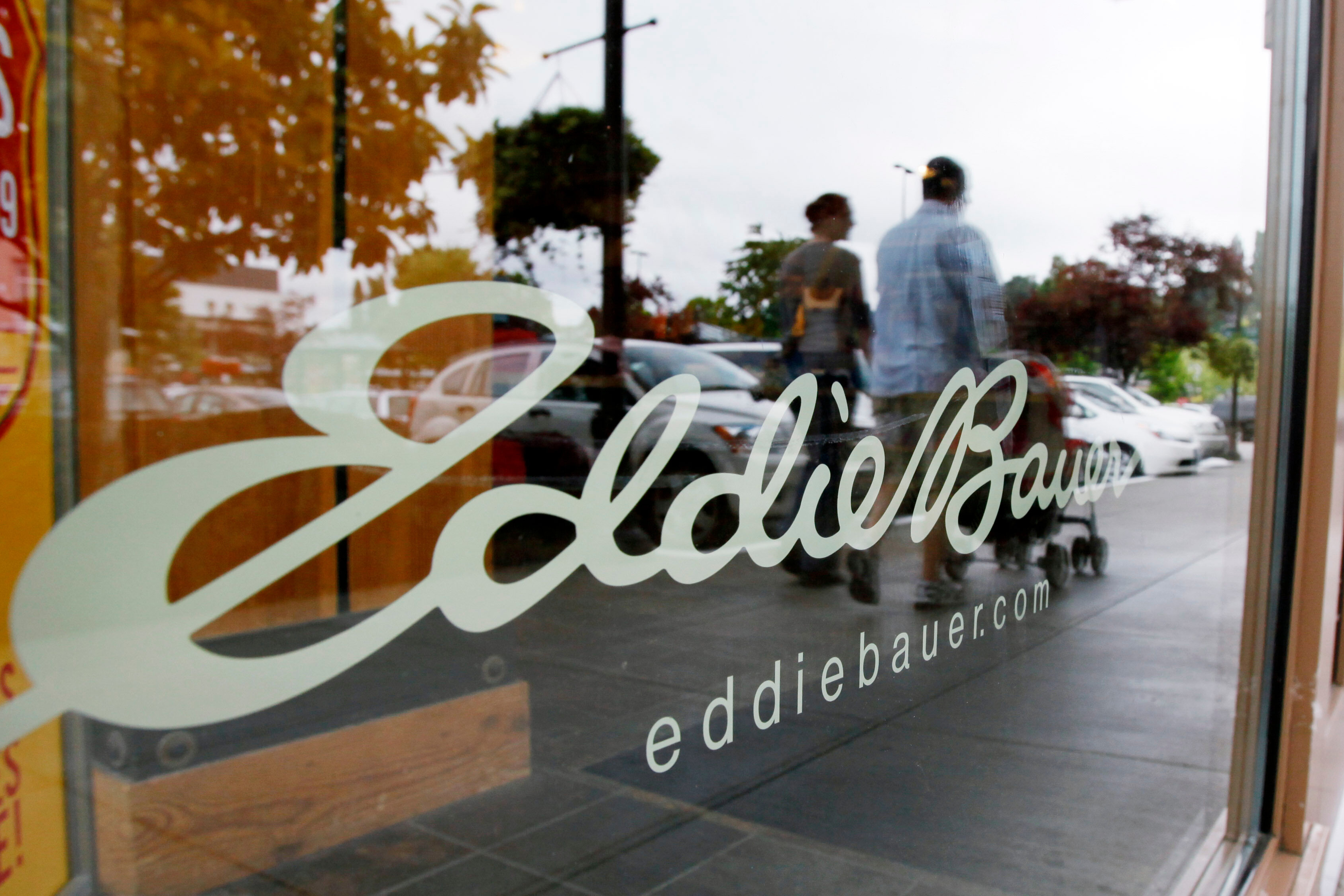 caption: FILE - In this June 17, 2009, file photo, shoppers are reflected in the window as they walk past an Eddie Bauer store, in Seattle. 