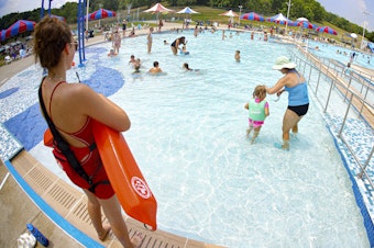 caption: Lifeguard Maggie Storti (left) keeps an eye on visitors to the North Boundary Park swimming pool and waterpark on July 9, 2020, in Cranberry Township, Pa.