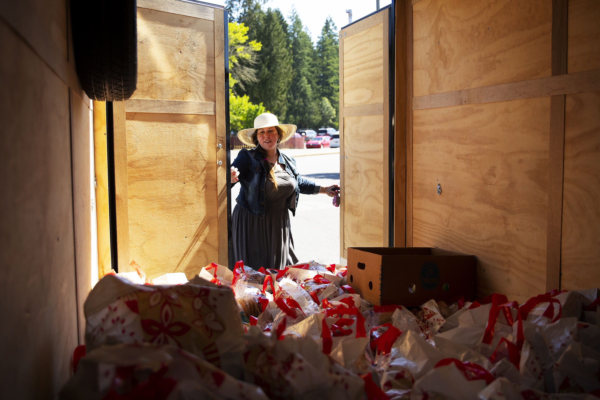 caption: Volunteer Shelley Acuña opens her trailer before unloading bags of food for students at Concrete Elementary School on Monday, June 12, 2023, in Concrete. 