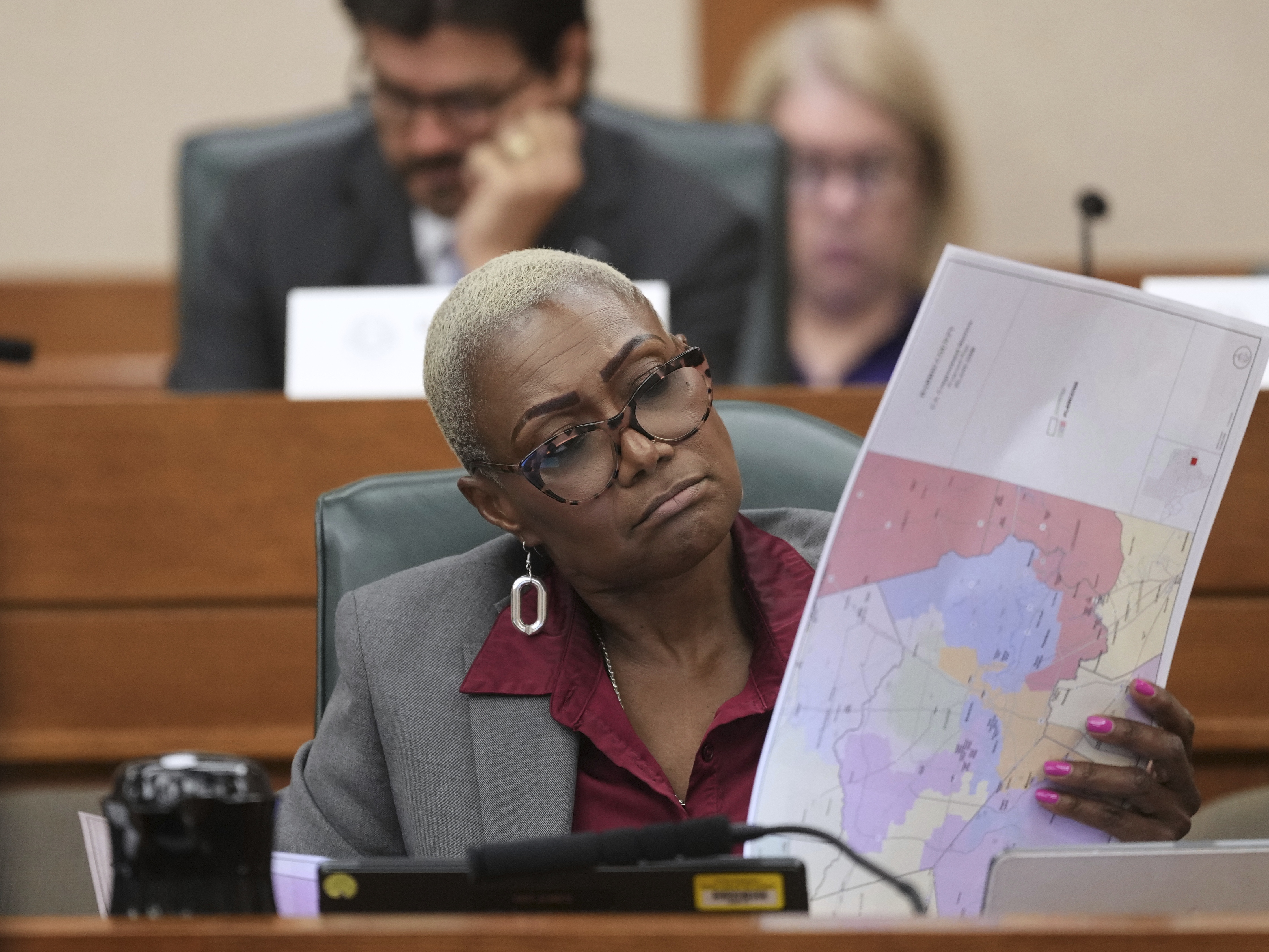 caption: Texas state Rep. Jolanda "Jo" Jones, a Democrat, flips through maps during a public hearing on congressional redistricting in Austin, Texas, on Aug. 1. After the bill passed the committee, state Democrats fled to Illinois and New York to break the quorum and stall a vote on the new maps, which heavily favor Republicans.