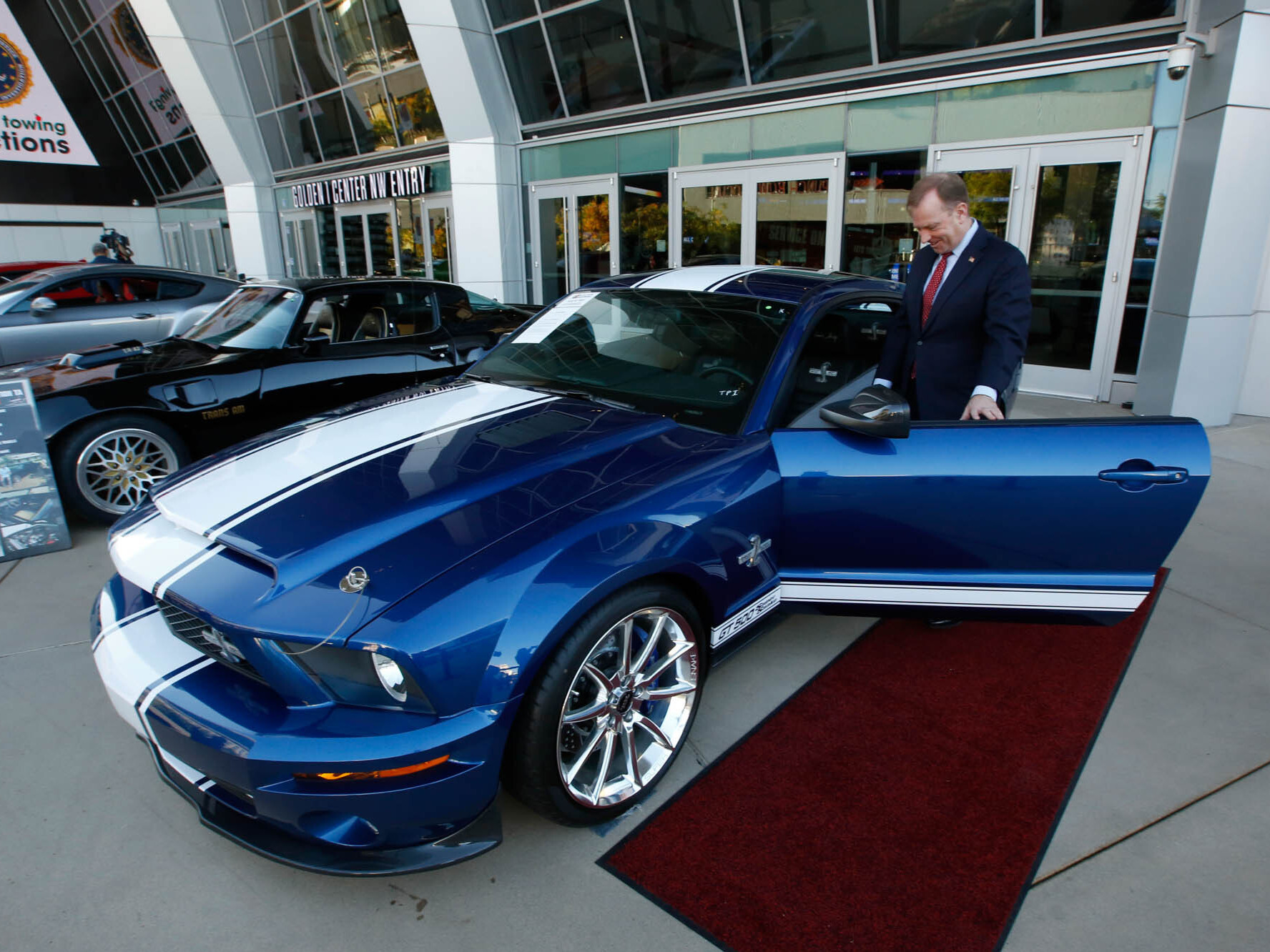 caption: McGregor Scott, who was the the U.S. Attorney for the Eastern District of California in 2019, looks over a cars seized from Jeff and Paulette Carpoff in Sacramento, Calif. The Carpoffs owned a San Francisco Bay Area solar energy company and pleaded guilty for participating in what federal prosecutors called a massive Ponzi scheme that defrauded investors of $1 billion.