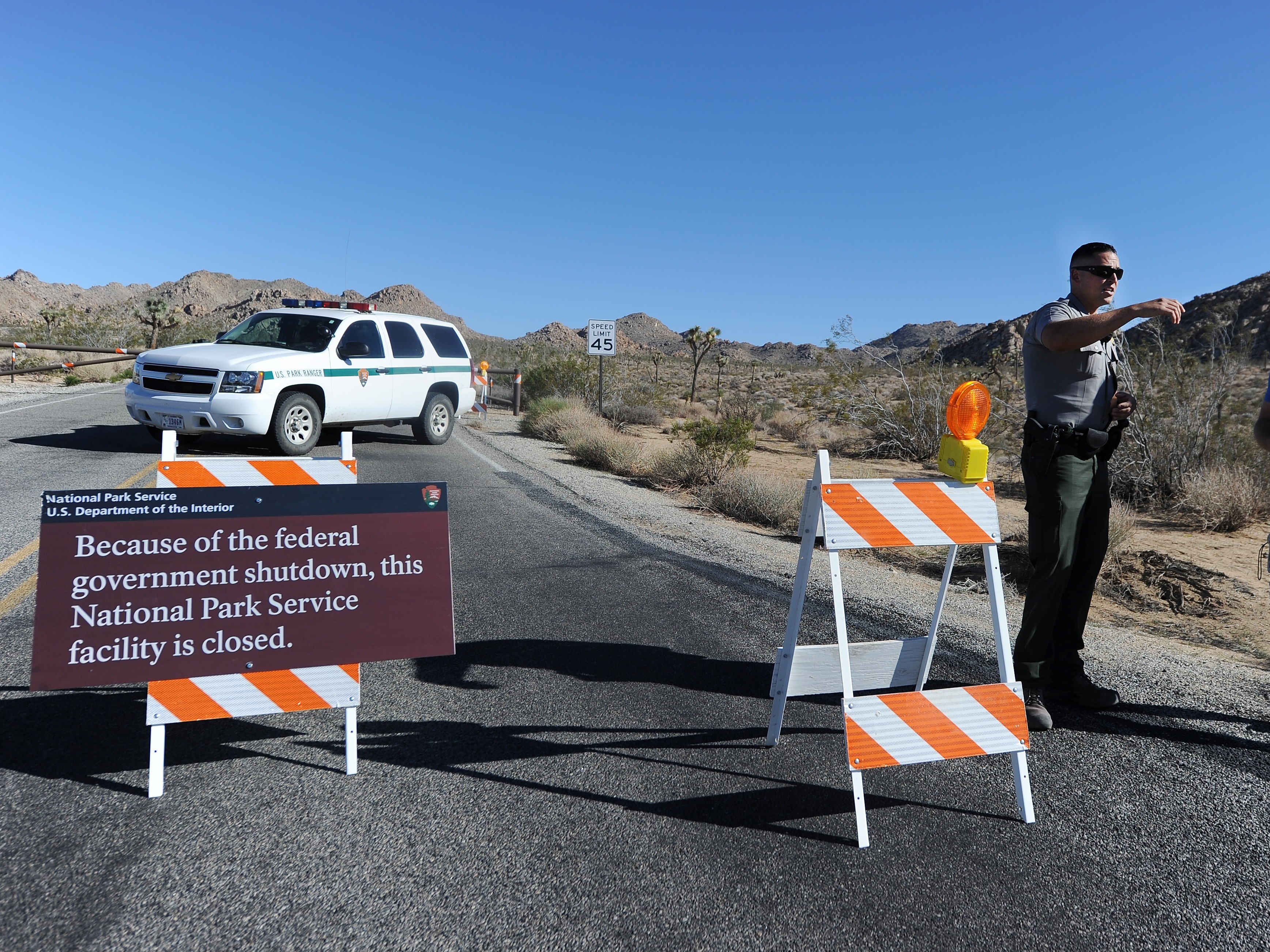 caption: A U.S. park ranger gives a visitor suggestions of other nearby places he can visit while Joshua Tree National Park was shutdown in 2013.