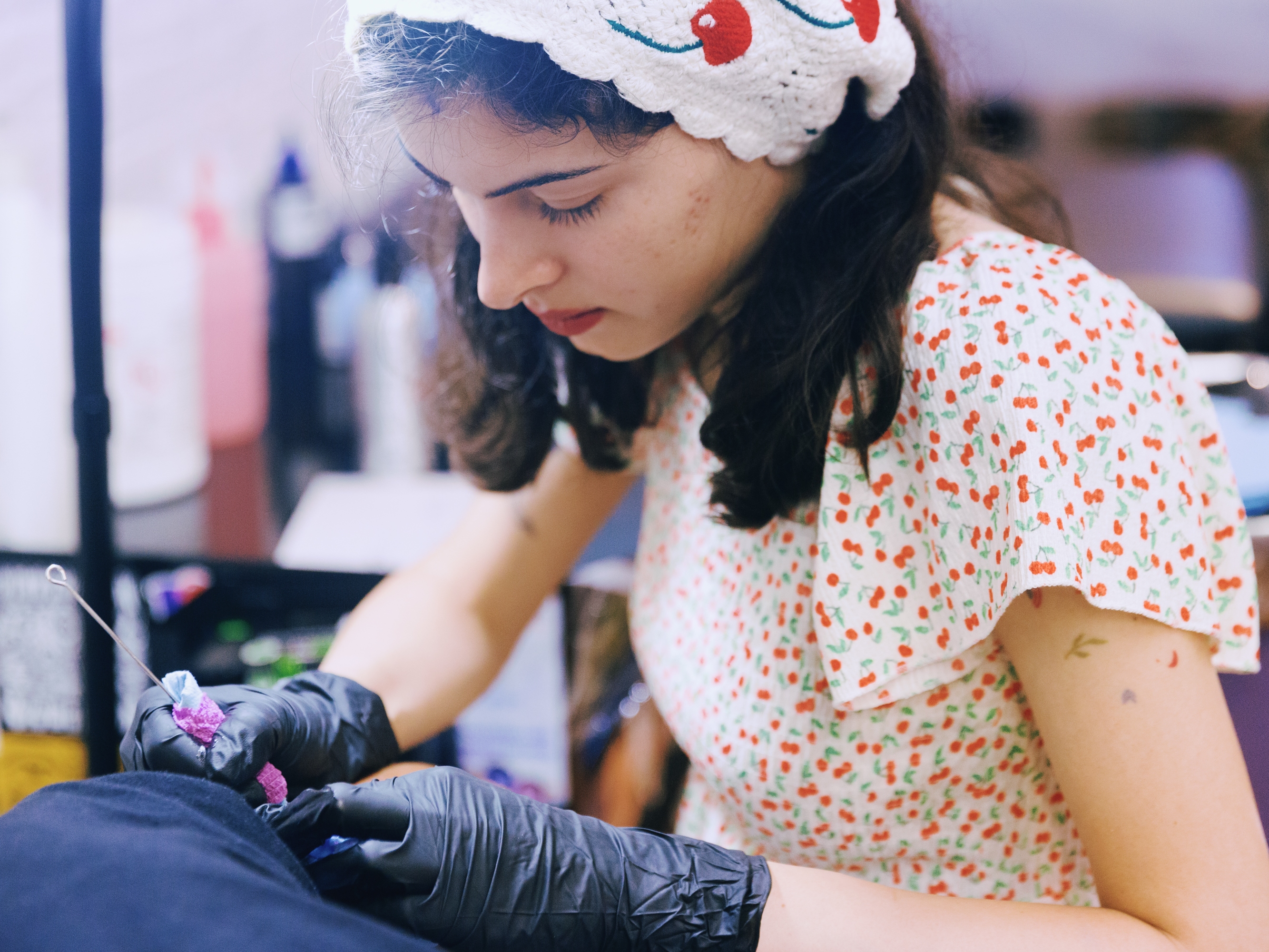 caption: Abby Ingwersen, a guest artist at Nice Try Tattoo, works on a client using the stick and poke method.