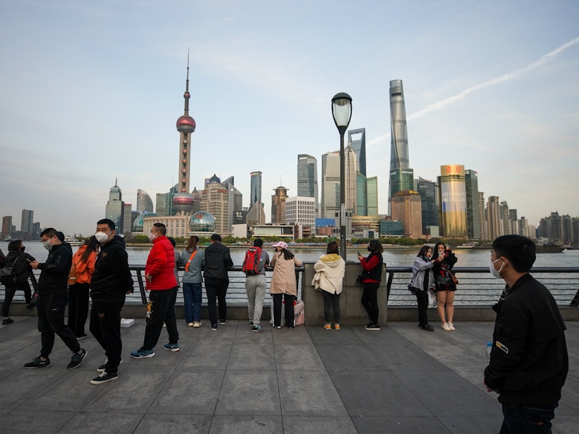 caption: People gather along the waterfront of the Bund on Tuesday in Shanghai.