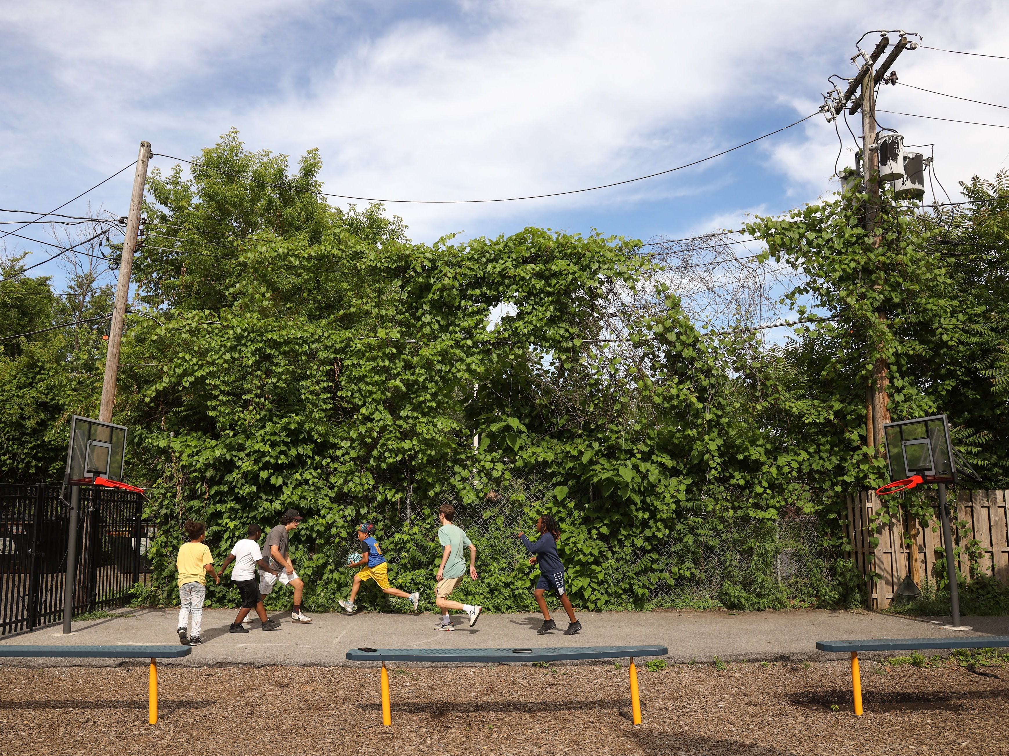 caption: Volunteers from McQuaid Jesuit High School play basketball with the children of Cameron Community Ministries' after-school program.