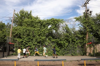 caption: Volunteers from McQuaid Jesuit High School play basketball with the children of Cameron Community Ministries' after-school program.