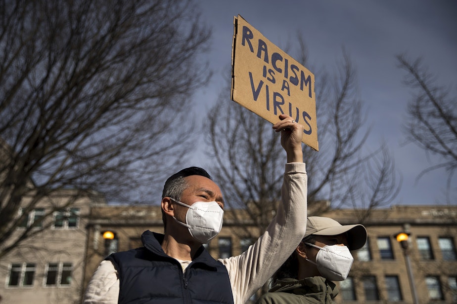 caption: Michael Lee holds a sign in the air that reads 'Racism Is a Virus,' as hundreds gathered for the 'We Are Not Silent' rally and march against the rise in racist violence toward both Asian American and Pacific Islander communities at Hing Hay Park in Seattle's Chinatown-International District.