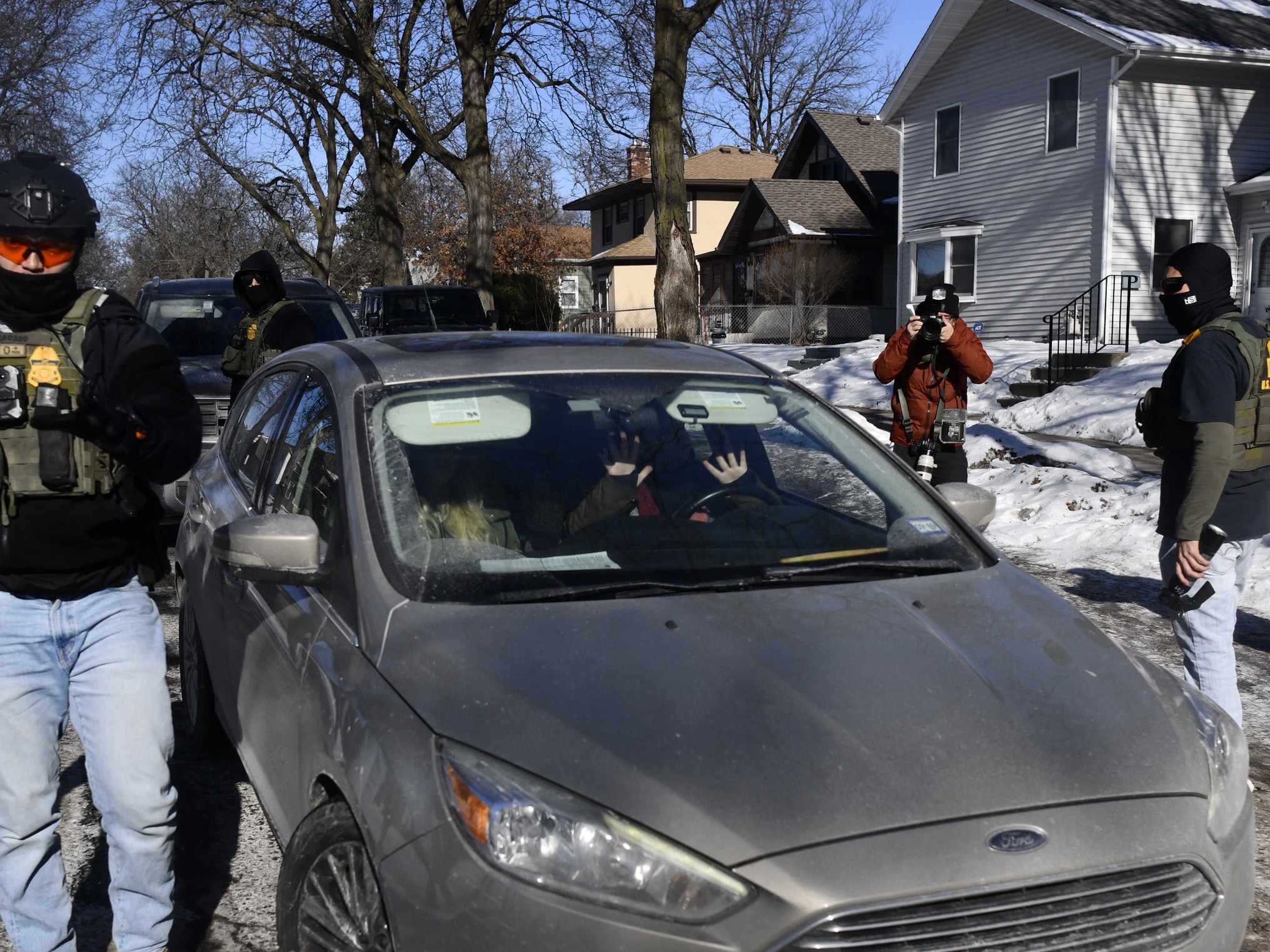 caption: Federal immigration agents confront observers monitoring their activity from inside their cars while patrolling a neighborhood in Minneapolis on Jan. 29.