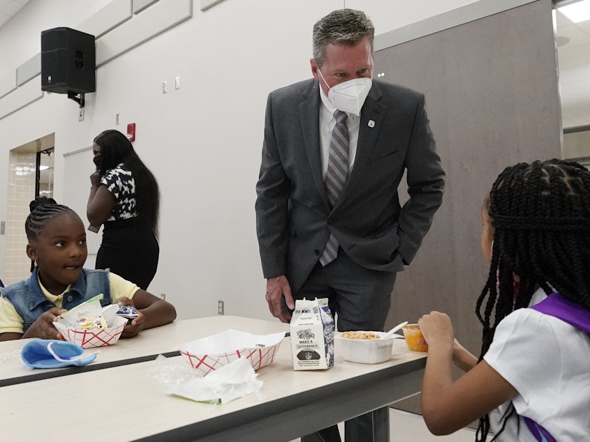 caption: Mike Burke, Palm Beach County superintendent of schools, chats with students as they eat breakfast on Tuesday. The school district has asked 440 students to quarantine just days into the school year.