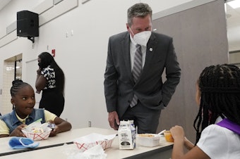 caption: Mike Burke, Palm Beach County superintendent of schools, chats with students as they eat breakfast on Tuesday. The school district has asked 440 students to quarantine just days into the school year.