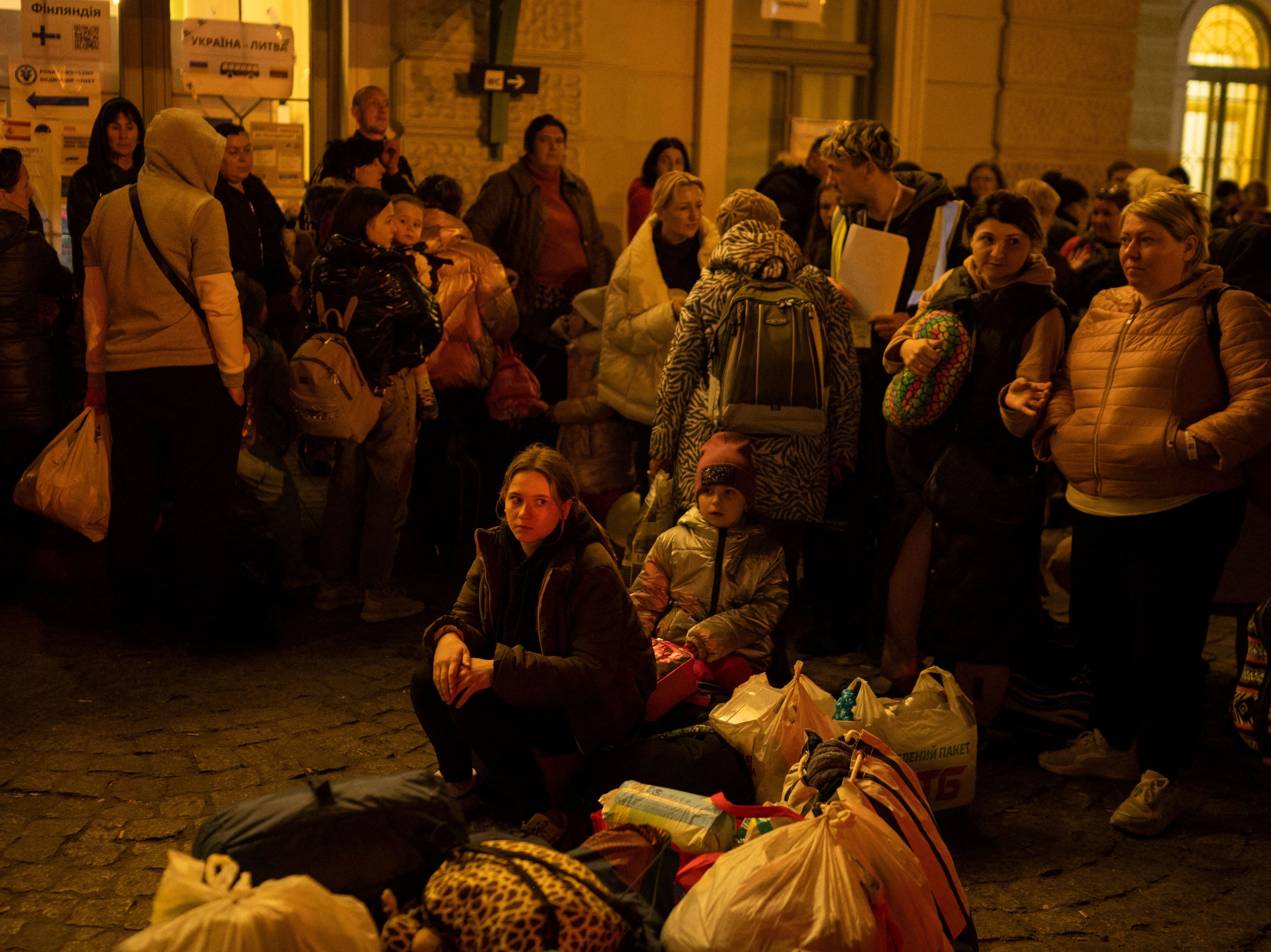 caption: Refugees from Ukraine wait to get on buses to other destinations in Poland, outside the train station in Przemysl, near the Ukrainian-Polish border in southeastern Poland, on Wednesday.