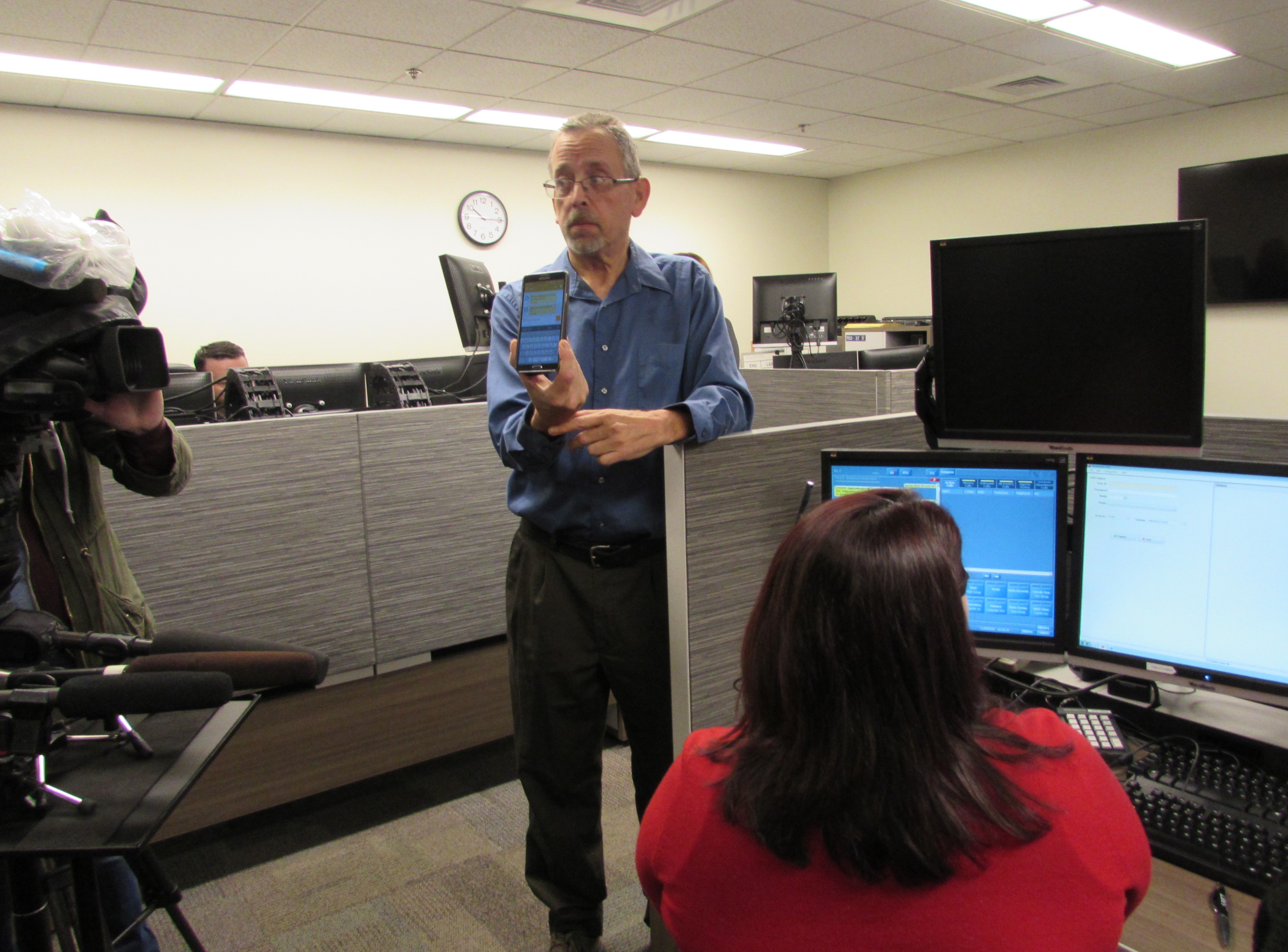 caption: King County can now accept text messages to 9-1-1. Jim House, who is deaf, shows how he could report a crime to Michele Torresdiaz, in red. 