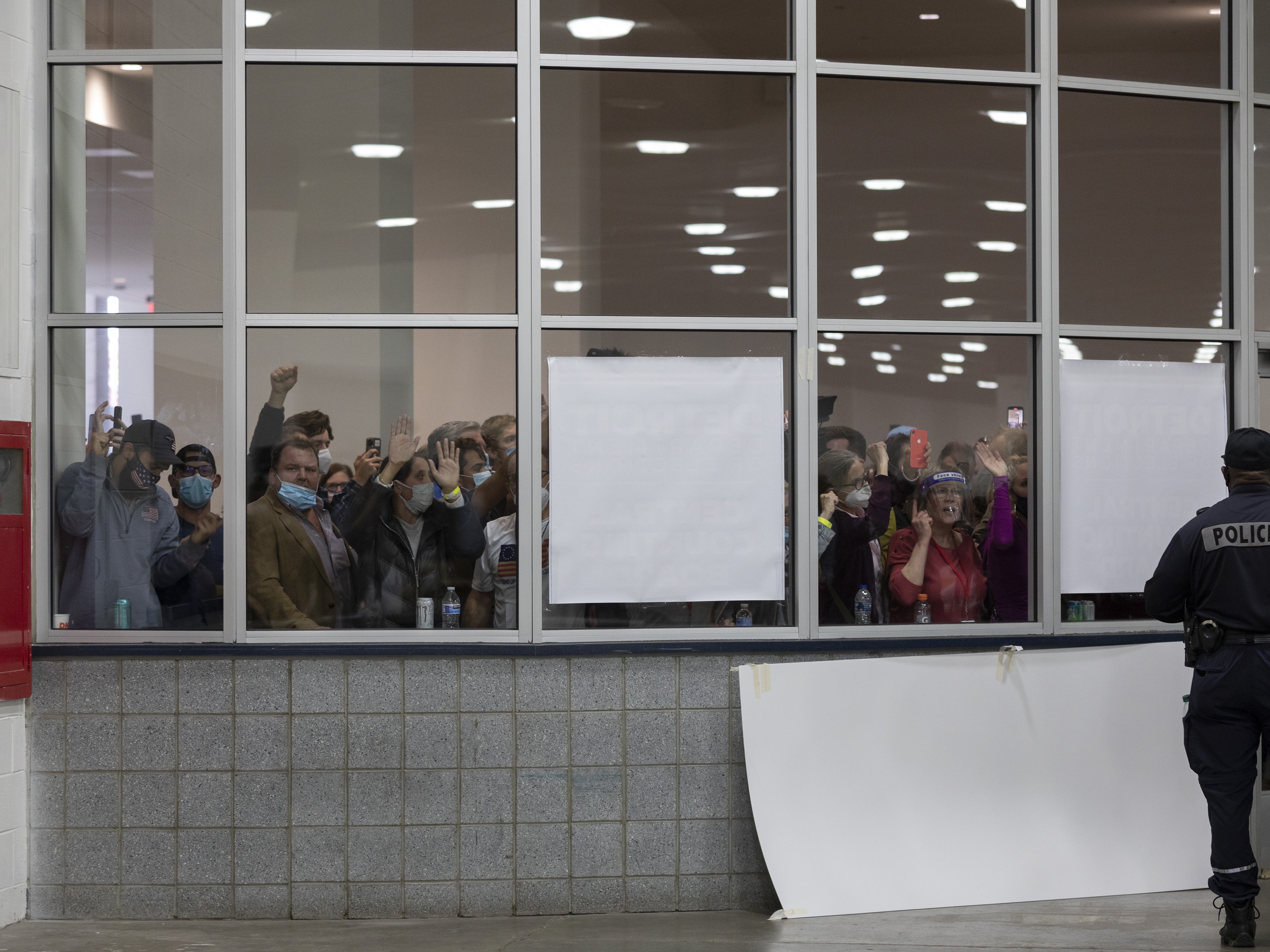 caption: A crowd chants "Stop the count!" and pounds on the windows and doors after partisan election challengers were told that the capacity for election challengers had been met in the counting facility at what was then Detroit's TCF Center on Nov. 4, 2020.