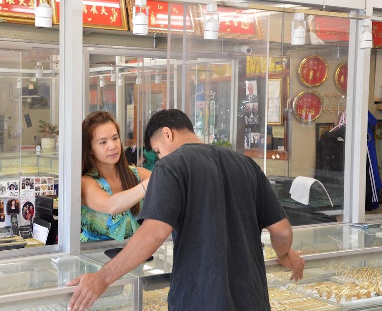 caption: Phillip Dang’s wife, Lynette, helps a customer select a piece of jewelry.
