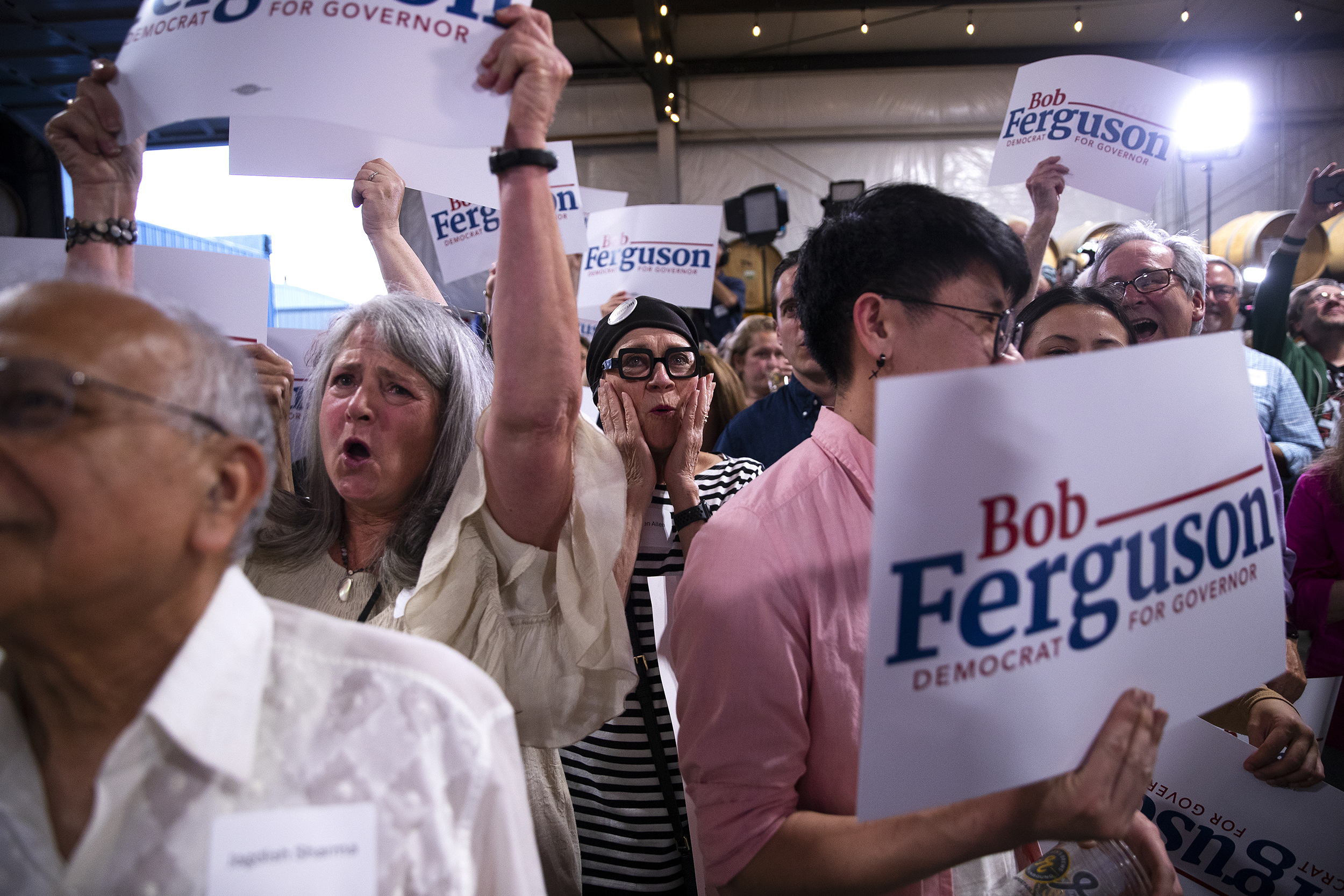 caption: Supporters, including Kathleen Allen, center, cheer for  Bob Ferguson, the Democrat gubernatorial candidate for Washington state, during a primary election night party on Tuesday, August 6, 2024, at Reuben’s Barrel House event space in Seattle. 