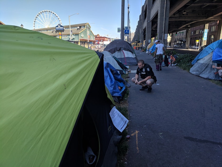 caption: Tents are lined up under the viaduct in Seattle as members of the City's Navigation Team are doing outreach. 