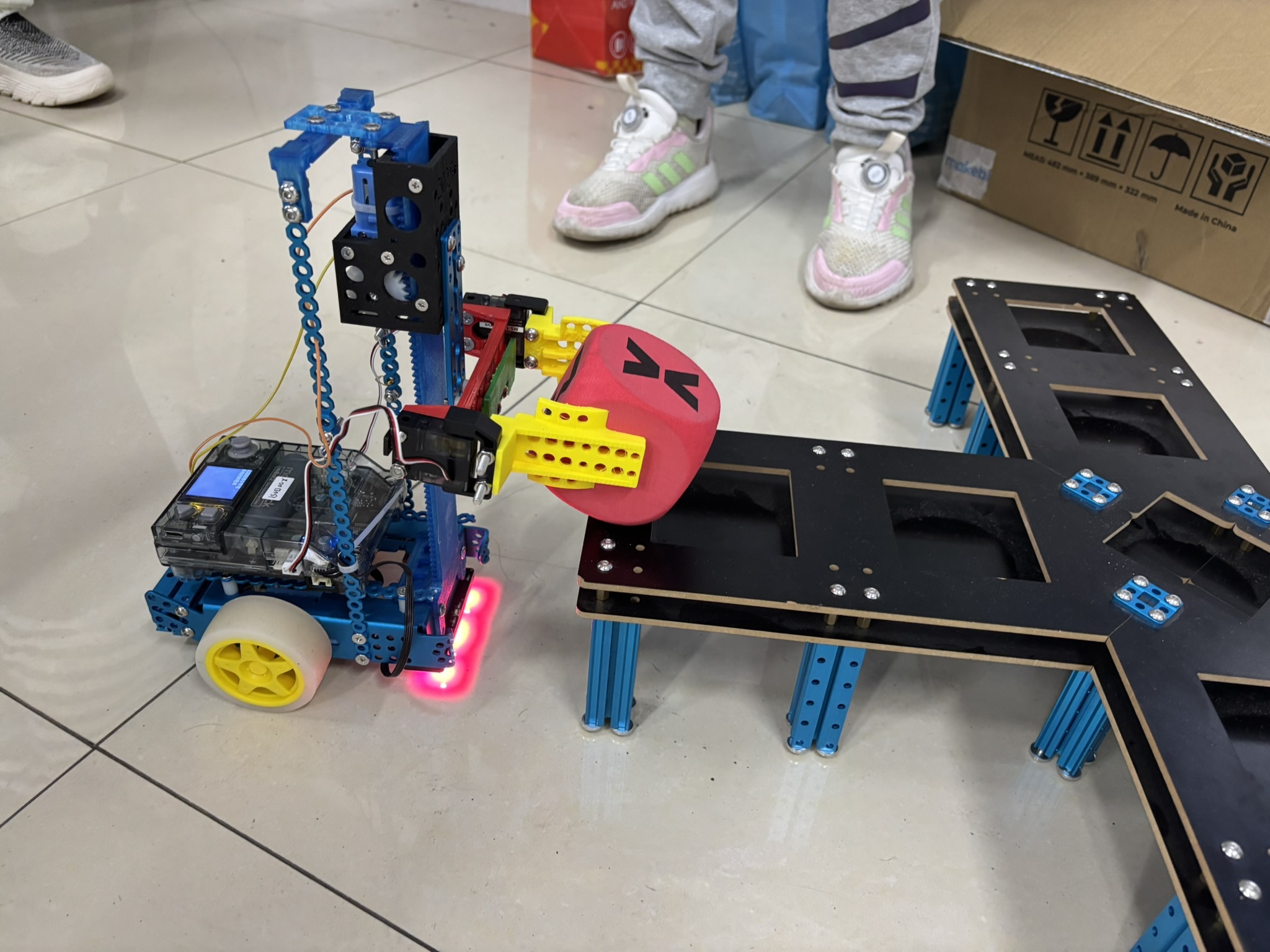 caption: Li Zichen, a fifth grader at a Chinese public school, demonstrates a remote-controlled robot that can lift and move blocks and be programmed using artificial intelligence.