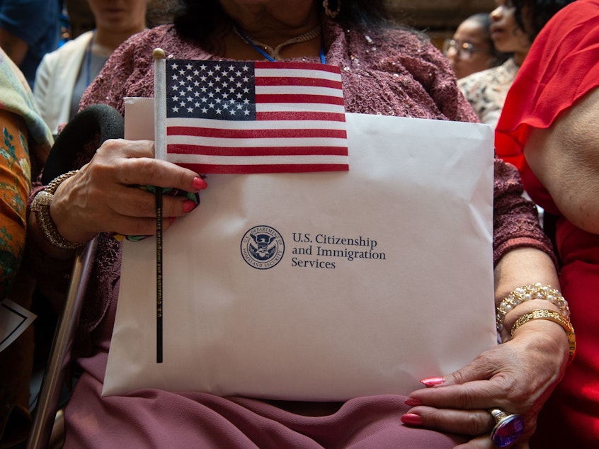 caption: A newly sworn-in U.S. citizen holds the U.S. flag and paperwork during a 2018 naturalization ceremony in New York City. The Department of Homeland Security has agreed to share its records with the U.S. Census Bureau to help produce data about the U.S. citizenship status of every person living in the country, as ordered by President Trump.