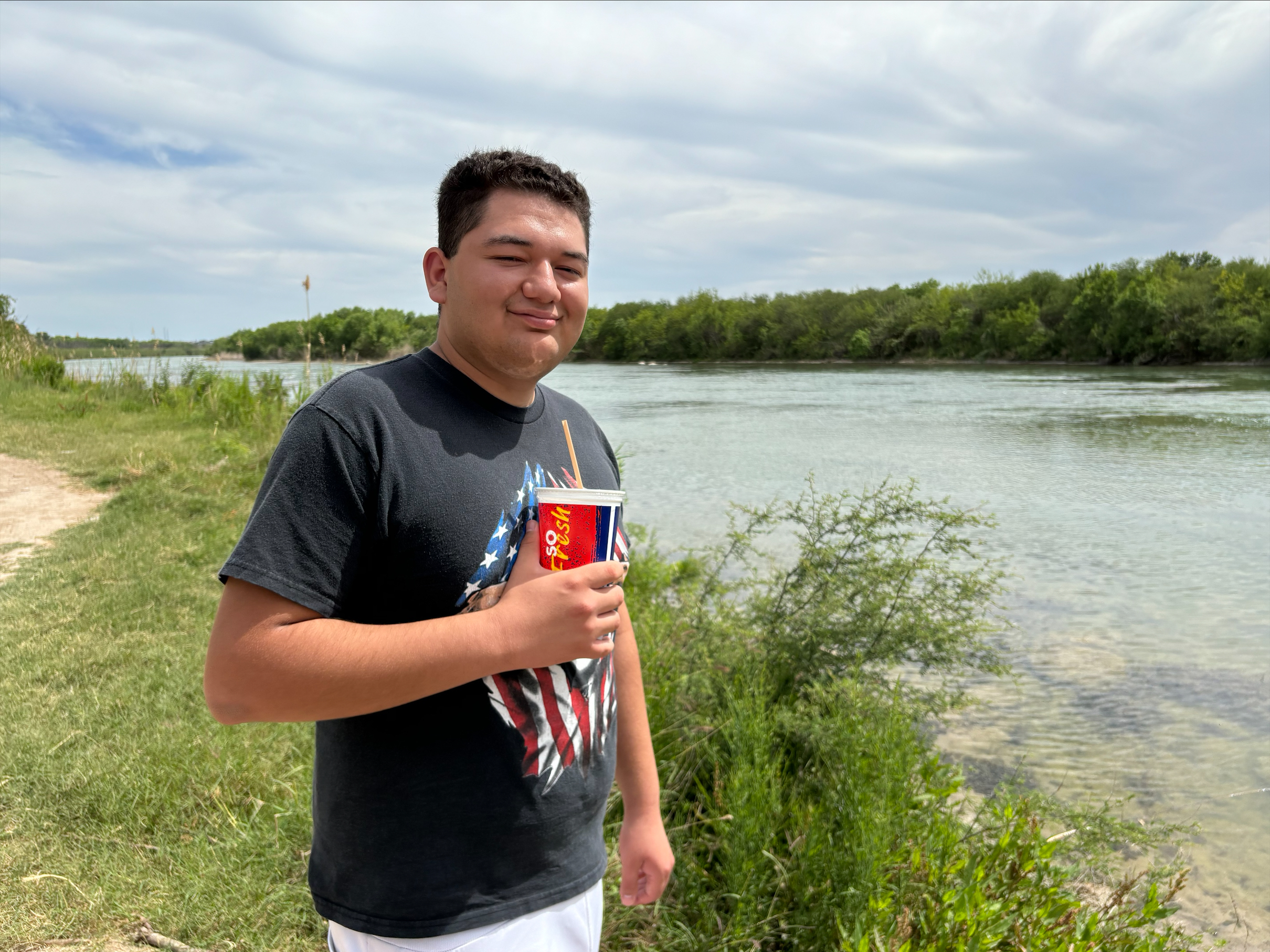 caption: Rashaan Soto, 19, poses in front of a section of the Rio Grande in Eagle Pass, Texas on April 6,. 2024.