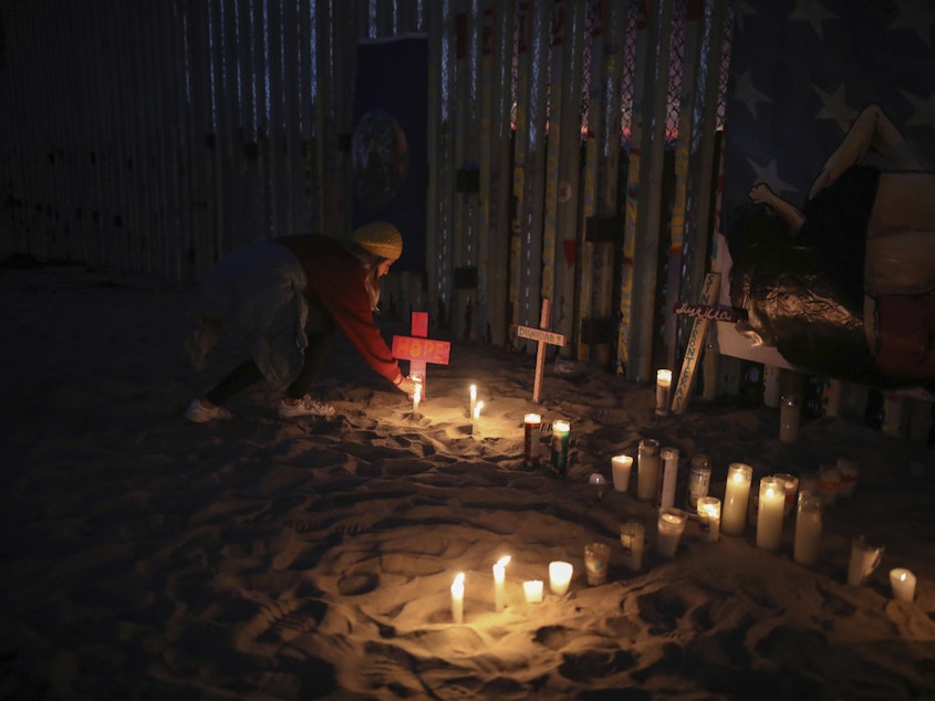 caption: Candles are placed next to the U.S.-Mexico border fence earlier this year in Tijuana, Mexico, in memory of migrants who have died during their journey toward the U.S.