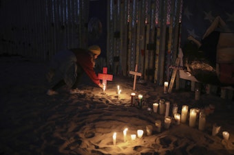 caption: Candles are placed next to the U.S.-Mexico border fence earlier this year in Tijuana, Mexico, in memory of migrants who have died during their journey toward the U.S.