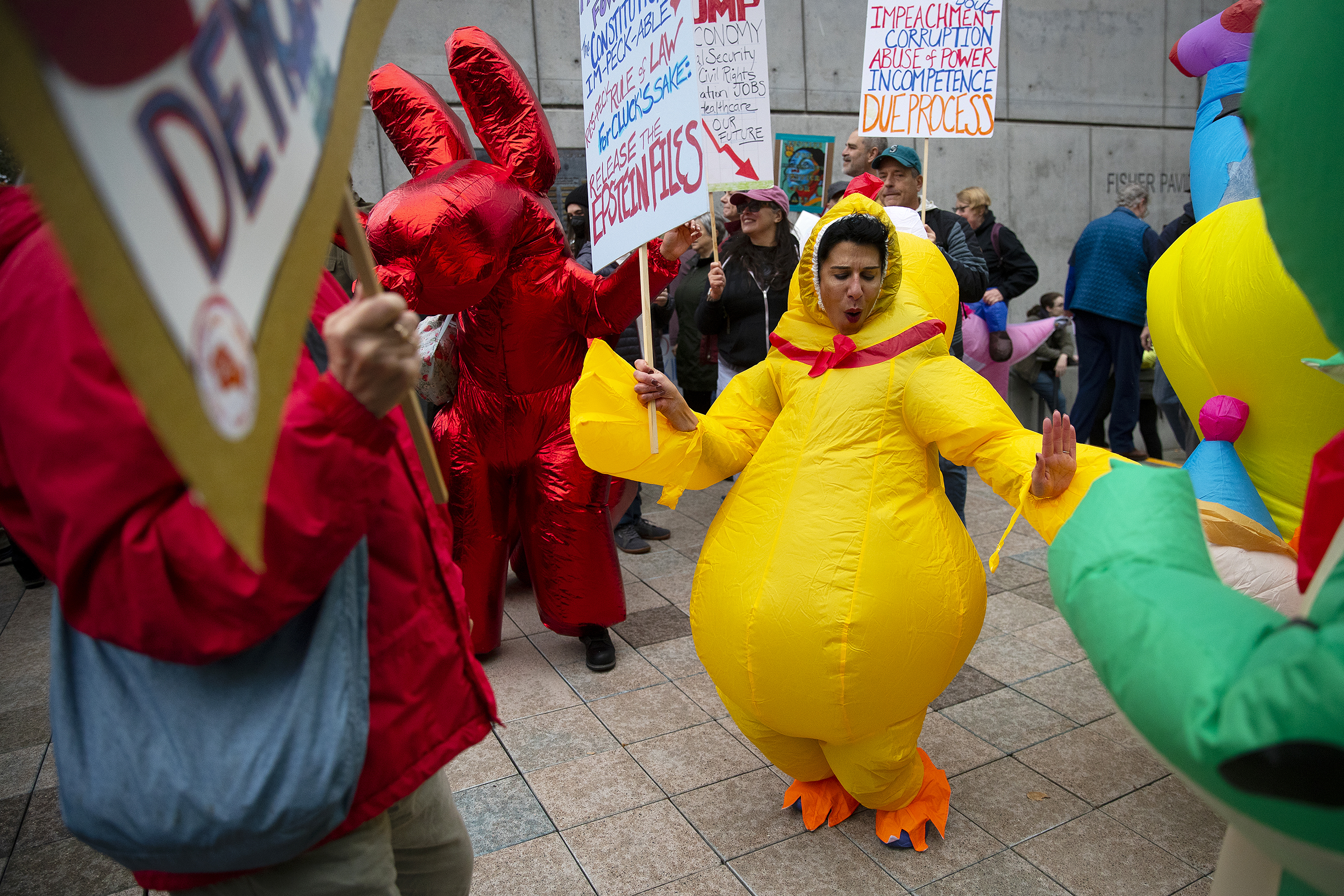 caption: Protesters, including Amina Suchoski, center, dance and laugh while dressed in inflatable costumes during the No Kings rally on Saturday, October 18, 2025, at Seattle Center. 