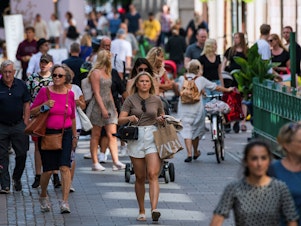 caption: People walk in Stockholm on July 27, most without the face masks that have become common on the streets of many other countries as a method of fighting the spread of the coronavirus.
