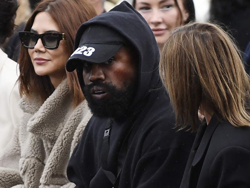 caption: Ye (C), formerly known as Kanye West, attends the Givenchy Spring-Summer 2023 fashion show during the Paris Womenswear Fashion Week, in Paris, on Oct. 2, 2022.