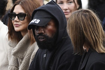 caption: Ye (C), formerly known as Kanye West, attends the Givenchy Spring-Summer 2023 fashion show during the Paris Womenswear Fashion Week, in Paris, on Oct. 2, 2022.