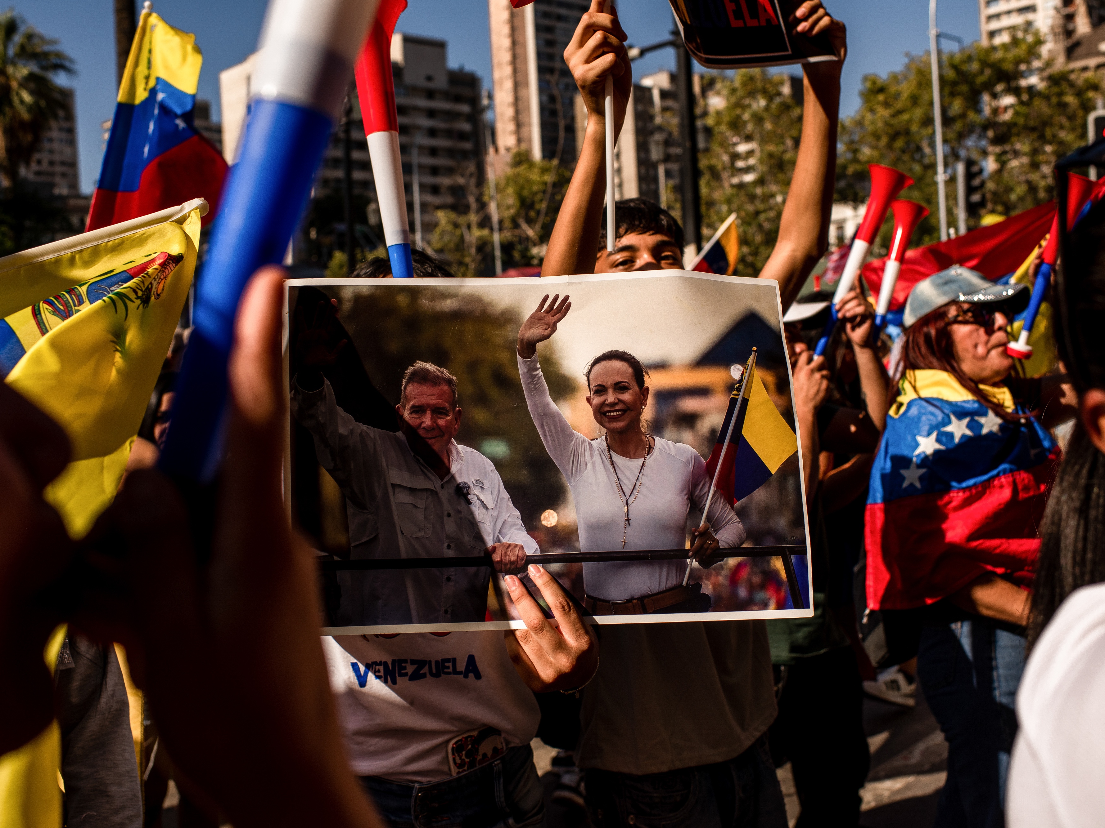 caption: A resident holds an image of Venezuelan opposition leader María Corina Machado during a celebration in Santiago, Chile, on Saturday, after U.S. forces seized Venezuela's leader Nicolás Maduro.