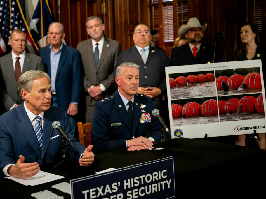 caption: Texas Gov. Greg Abbott (left) speaks about a new border security measure during a news conference at the Texas State Capitol on June 8.