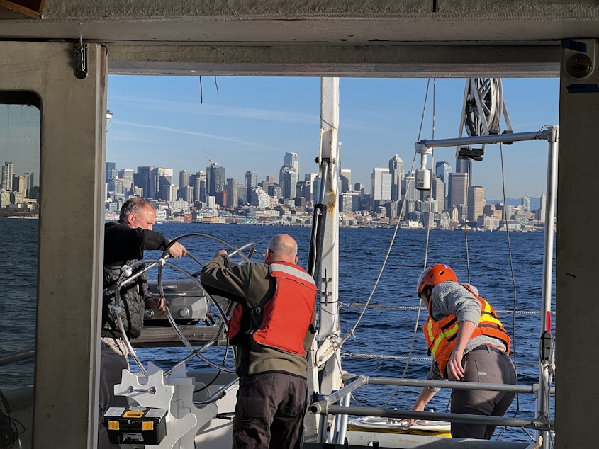 caption: The crew lefts a steel cage that will mount to the ROV. Using an A-frame pully, it will then be dropped from the ship into the bay.