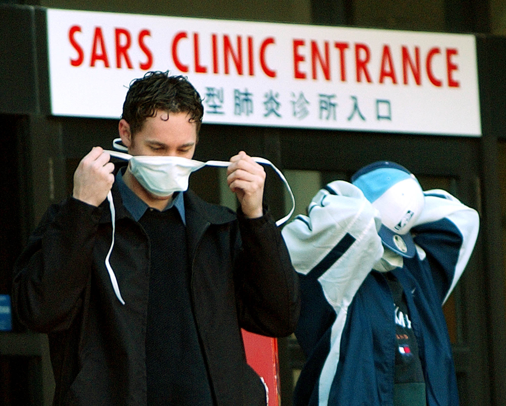 caption: Patients put on face masks as they leave the SARS (Severe Acute Respiratory Syndrome) clinic setup at Sunnybrook & Women's hospital in Toronto, Canada, on 31 March, 2003. (J.P. MOCZULSKI/AFP via Getty Images)
