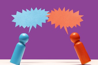 One blue and one red wooden figurine face each other under their own respective spiky speech bubbles, representing a combative verbal exchange.