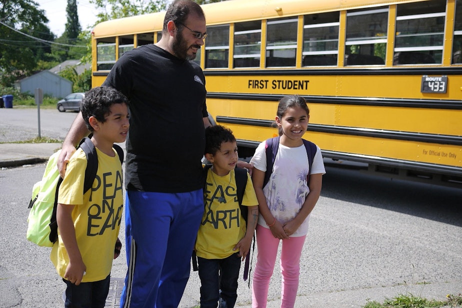 caption: Bassam Alhamdan, father of six, meets his kids at the bus stop every afternoon.