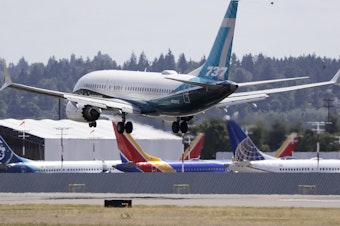 caption: A Boeing 737 Max heads to a landing past grounded 737 Max aircraft at Boeing Field following a test flight Monday in Seattle. The jet took off from Boeing Field earlier in the day, the start of three days of re-certification test flights that mark a step toward returning the aircraft to passenger service.