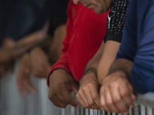 caption: Migrants wait at the Gateway International port of entry under U.S. Customs and Border Protection custody in Brownsville, Texas, on May 5, before being sent back to Mexico under then-active Title 42 restrictions.