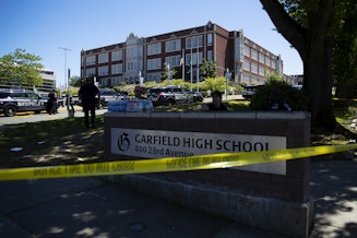 caption: Seattle police officers gather in the parking lot of Garfield High School following a shooting on Thursday, June 6, 2024, in Seattle. 