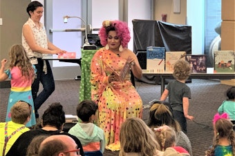 caption: A drag performer reads to families at a King County Library System Drag Queen Story Hour.